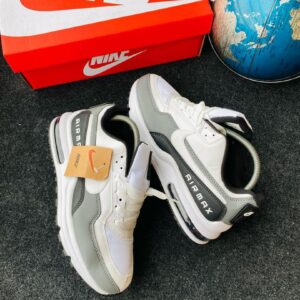 A pair of white and grey Nike Air Max shoes with a red Nike box and a blue globe in the background, perfect for sneaker enthusiasts in Nigeria.