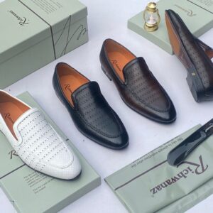 A pair of white perforated leather loafers from Richwanz, displayed on a shoe box with accessories.