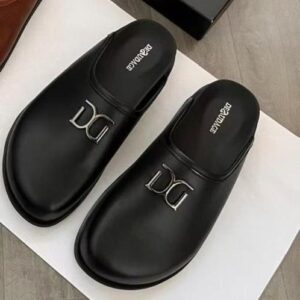 A pair of black leather slide sandals with a silver Dolce & Gabbana logo, placed on a white box.