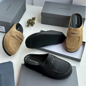 Luxury Balenciaga moccasin loafers in tan and black, displayed with boxes and a decorative item, showcasing high-class comfort and style.