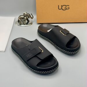 A pair of luxury grey UGG slide sandals displayed on a clean surface, with a golden elephant statue and UGG box in the background, showcasing high-class products for the elite in Nigeria.