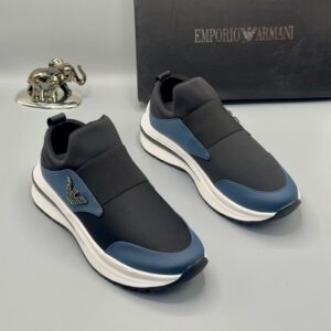 A pair of luxury Emporio Armani black and blue sneakers with white soles, displayed with a silver elephant statue and black box.