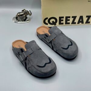 A pair of luxurious grey suede moccasin shoes for men, displayed with a silver elephant statue and a cardboard box, showcasing high-class products for the elite at Levonteluxe in Nigeria.