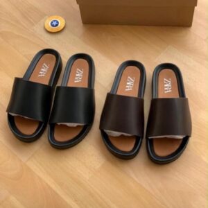 A pair of luxurious black slides with premium materials and attention to detail, presented with a box and packaging.
