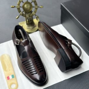 A pair of luxurious black leather monk strap shoes displayed on a white cloth, accompanied by a shoe tree and a decorative ship's wheel, epitomizing high-class elegance.