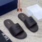 A pair of luxurious Dior slides with a sleek design and iconic logo, presented with a navy blue box and accessories on a light grey surface.