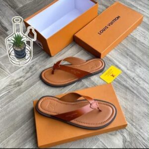 A pair of luxurious Louis Vuitton slides displayed on top of and next to their orange boxes, showcasing the premium quality and attention to detail.