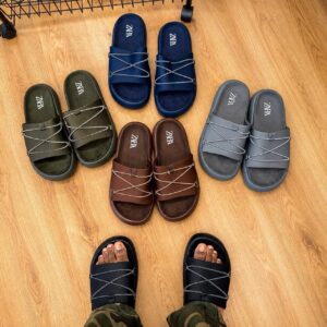 A carefully arranged display of six pairs of ZARA slides in various colors, including black, navy blue, brown, and grey, showcasing their sleek design and comfort.