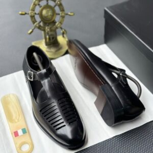 A pair of luxurious black leather monk strap shoes displayed on a white cloth, accompanied by a shoe tree and a decorative ship's wheel, epitomizing high-class elegance.