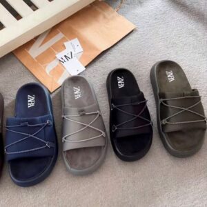 A carefully arranged display of six pairs of ZARA slides in various colors, including black, navy blue, brown, and grey, showcasing their sleek design and comfort.