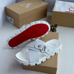 A pair of pristine white Christian slides, nestled on a brown shoe box with the brand's signature logo, exuding sophistication and refinement.